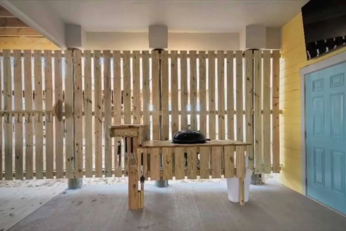 A cozy grilling and outdoor dining space with a wooden table set near a grill and a blue door, ideal for casual summer barbecues and social gatherings. The inviting setting hints at memorable evenings spent outdoors with friends and family.